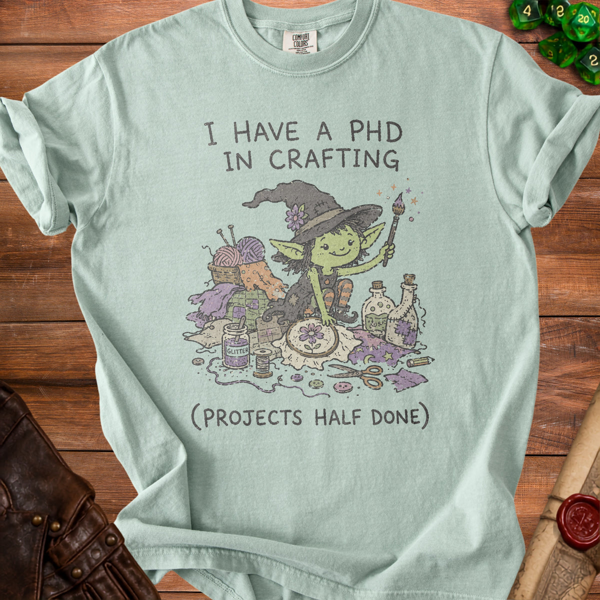 Light green t-shirt with "I HAVE A PHD IN CRAFTING (PROJECTS HALF DONE)" and a goblin crafting illustration.
