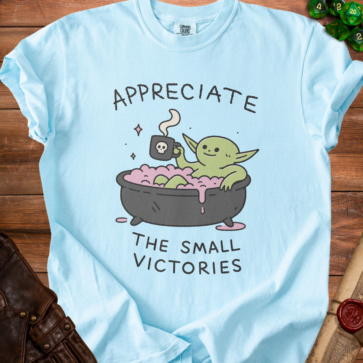 Light blue t-shirt with a cartoon goblin in a bathtub saying "Appreciate The Small Victories."