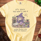 Light yellow t-shirt with cartoon witch graphic and text "IT'S SPICY YOU WON'T LIKE IT WHEN PEOPLE ASK WHAT I'M THINKING".