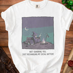 White t-shirt with graphic of a wizard by a campfire and text "NOT IGNORING YOU. JUST RECHARGING MY SOCIAL BATTERY."