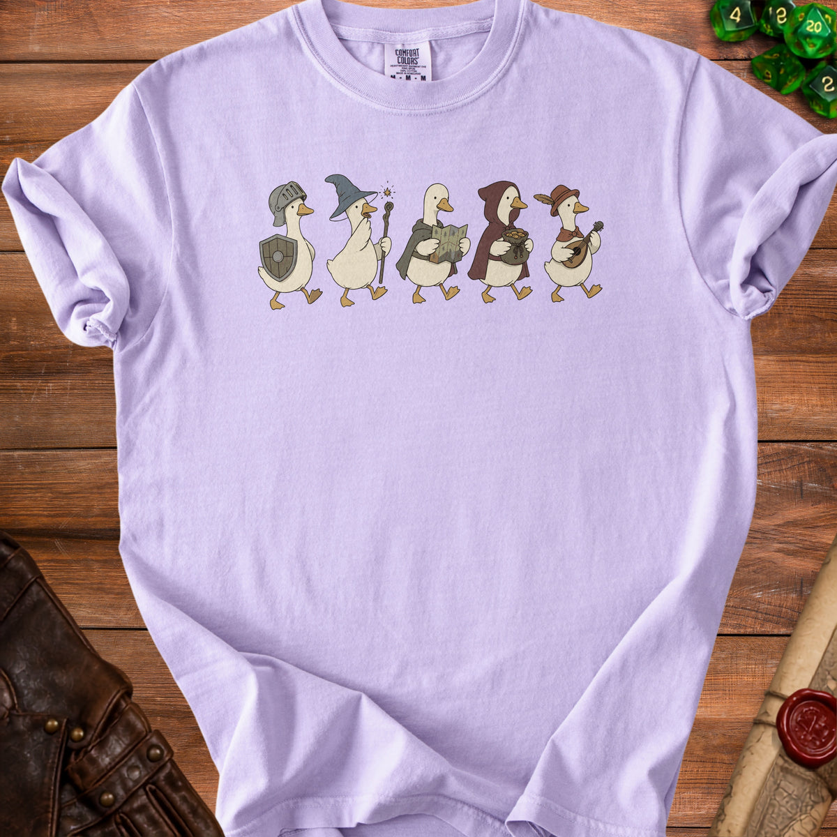 Lilac t-shirt with cartoon ducks dressed as fantasy adventurers walking in a line.