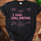 Black t-shirt with pink text: "I HAVE SMALL AMBITIONS", "tiny cottage", "mushroom garden", "good soup", "gentle hauntings", "zero prophecies", "no visitors".