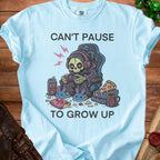 Light blue t-shirt with "Can't Pause To Grow Up" text and Grim Reaper gaming graphic.