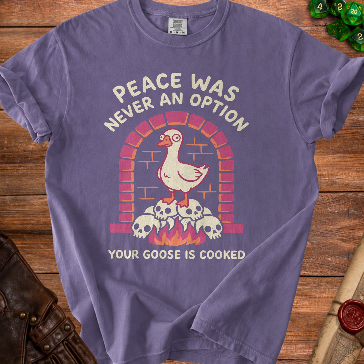 Purple t-shirt graphic with a goose on skulls above fire, text "Peace was never an option your goose is cooked".