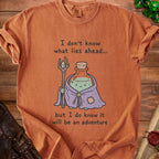 Orange t-shirt with "I don't know what lies ahead... but I do know it will be an adventure" text.
