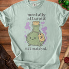 Light green t-shirt with a cute potion bottle and text "mentally attuned not matched."