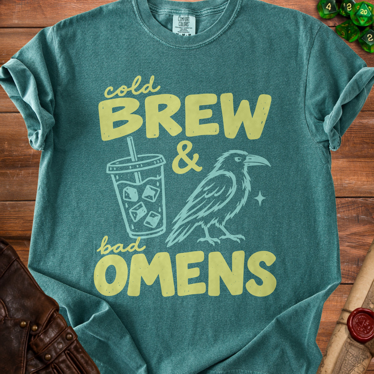 Green t-shirt with "cold BREW & bad OMENS" text and raven graphic.