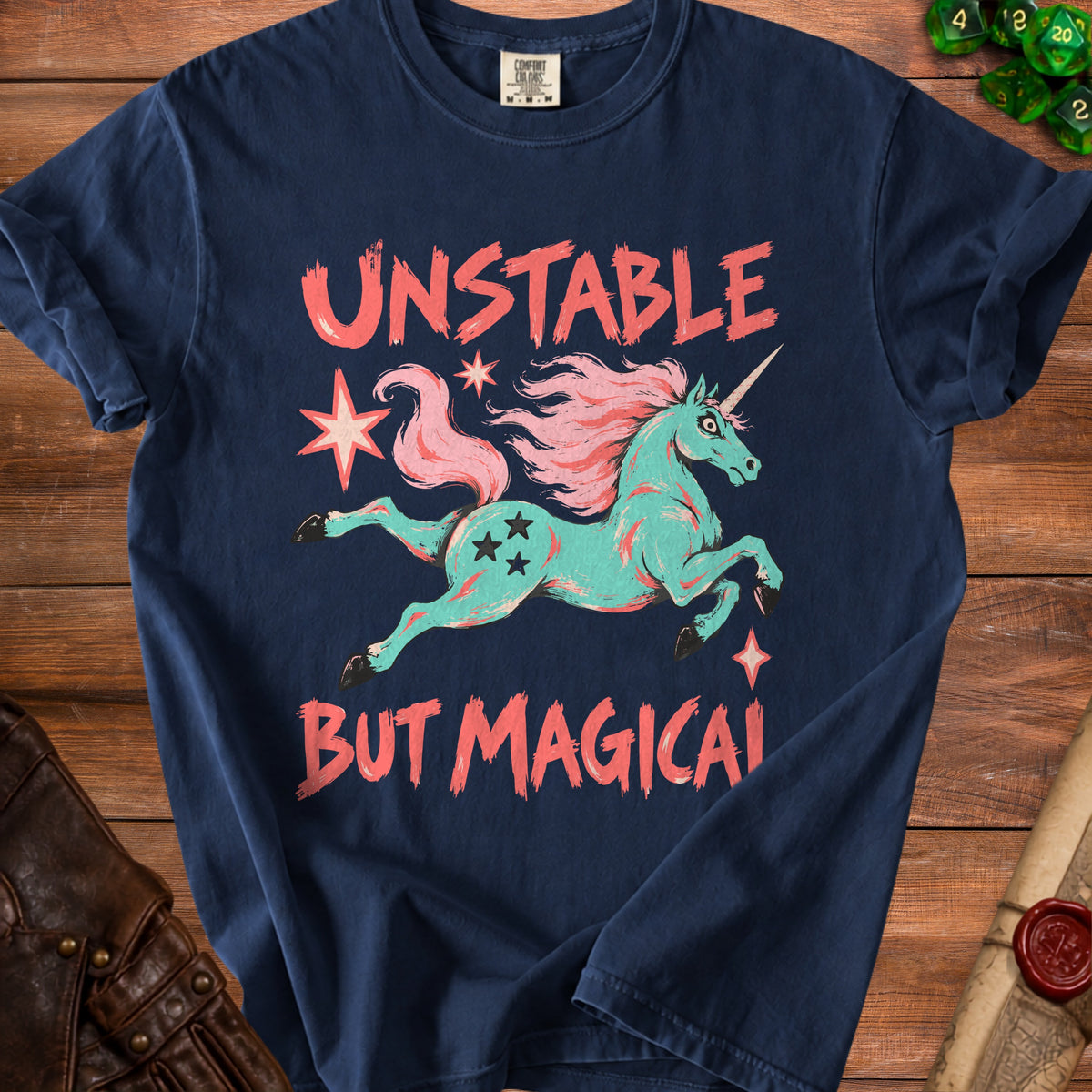 Navy blue t-shirt with teal unicorn graphic and text "UNSTABLE BUT MAGICAL".