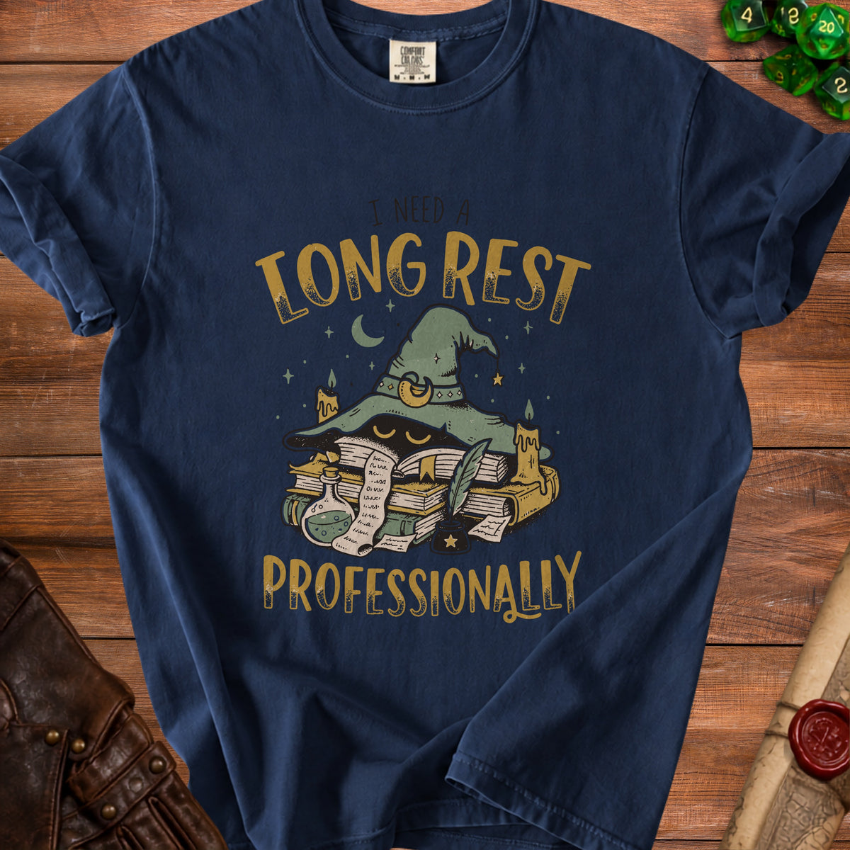 Dark blue t-shirt with a graphic of a witch's hat, books, and text: "I NEED A LONG REST PROFESSIONALLY".