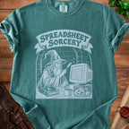 Green t-shirt graphic: wizard using quill on computer with "Spreadsheet Sorcery" banner.