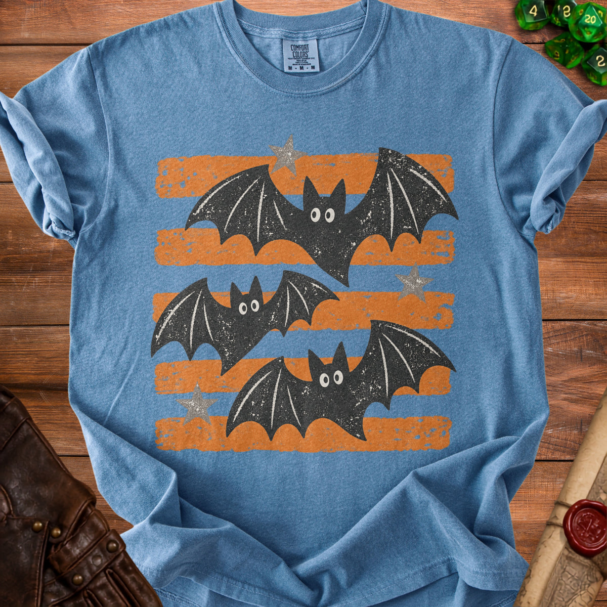 Blue t-shirt with three black cartoon bats and orange stripes on the chest.