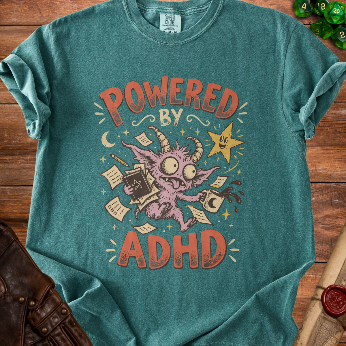 Teal t-shirt with "POWERED BY ADHD" text and a cartoon monster juggling papers.