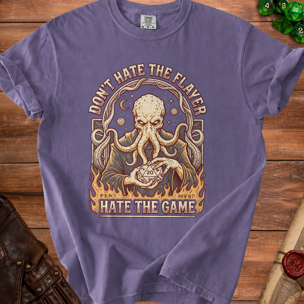 Purple t-shirt graphic with an octopus holding a twenty-sided die, text "Don't Hate the Flayer, Hate the Game."