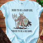 Light blue t-shirt with knight graphic and text "BORN TO BE A BABY GIRL FORCED TO BE A BIG DAWG."
