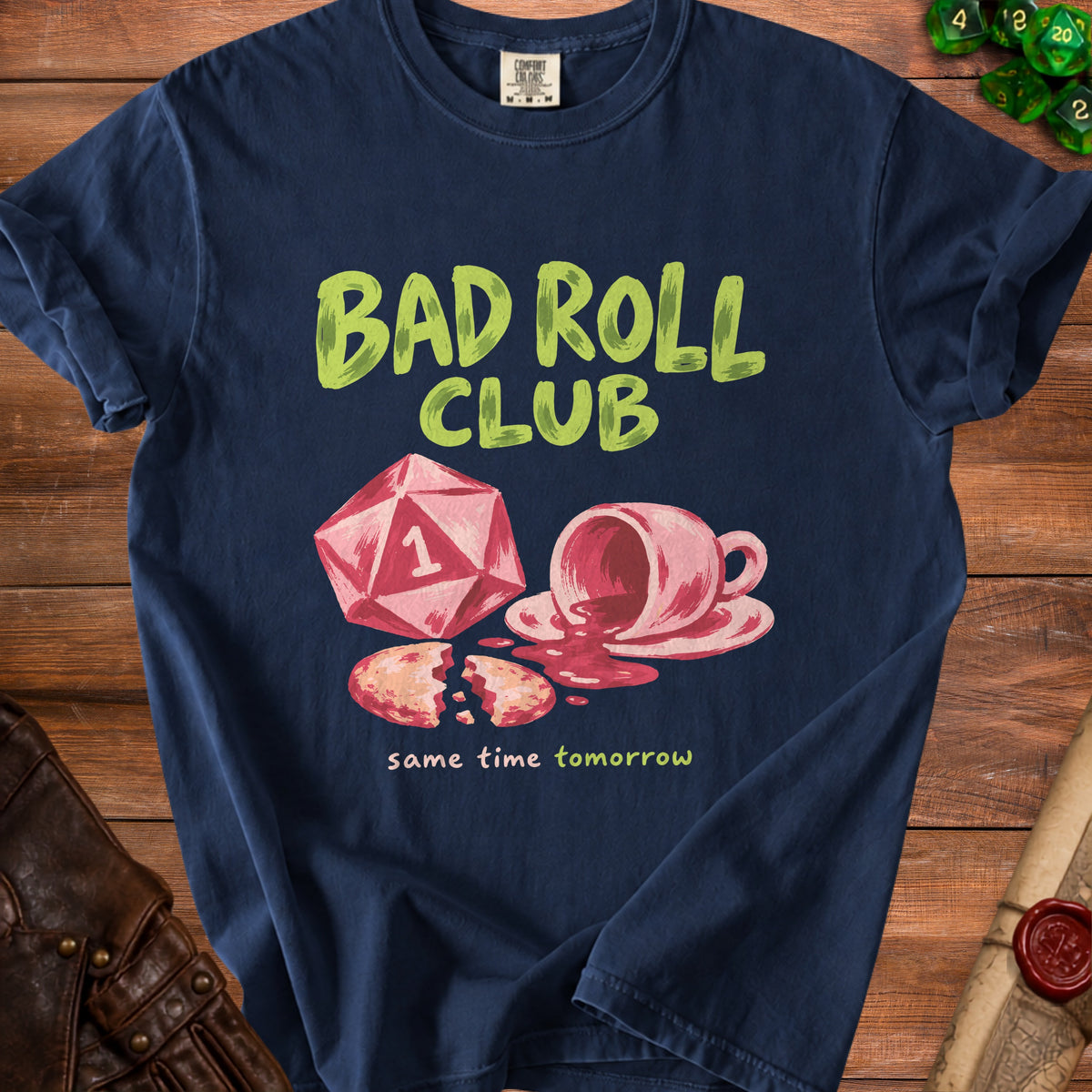 Navy t-shirt with "Bad Roll Club" text, a d20 die, spilled coffee, and a broken cookie.
