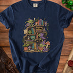 Navy t-shirt with illustration of goblins in a library with fantasy books and dice.