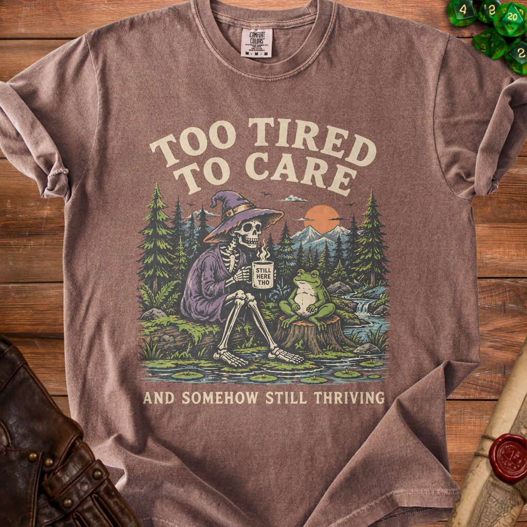 T-shirt with skeleton in witch hat and frog, reading "Too Tired To Care".