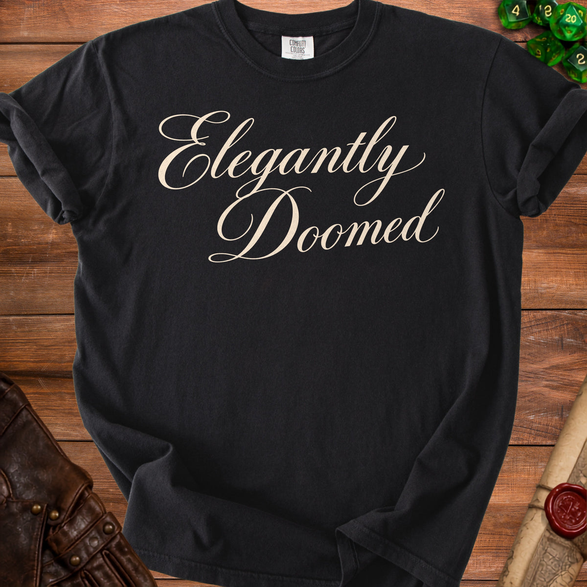 Black t-shirt with "Elegantly Doomed" in ornate cream lettering.