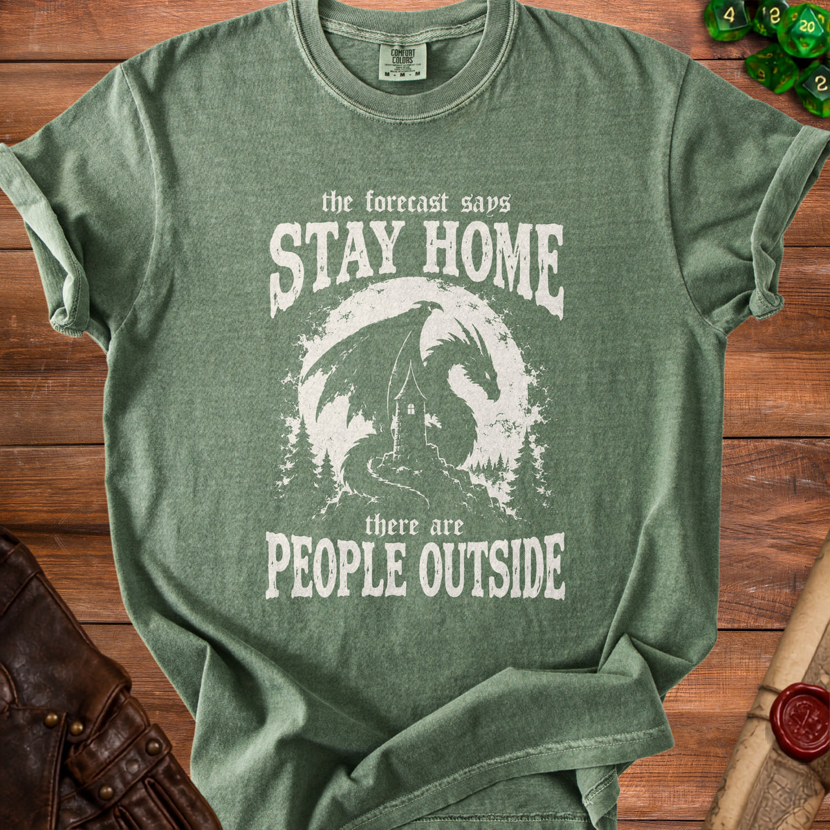 Green t-shirt with white text and dragon graphic: "The forecast says STAY HOME there are PEOPLE OUTSIDE".