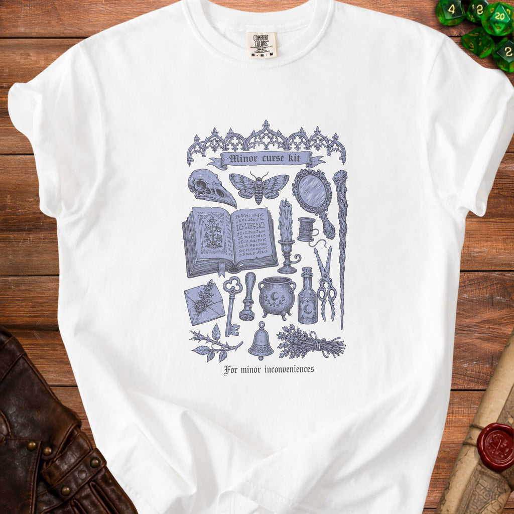 White t-shirt with a blue illustration of occult items and text "Minor curse kit".