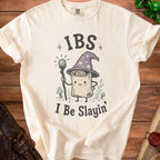 Cream t-shirt with graphic of a wizard scroll saying "IBS I Be Slayin'".