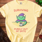 Yellow t-shirt with a cartoon goblin holding a mug that says "Mug of Spite" and text "Surviving Purely Out of Spite."