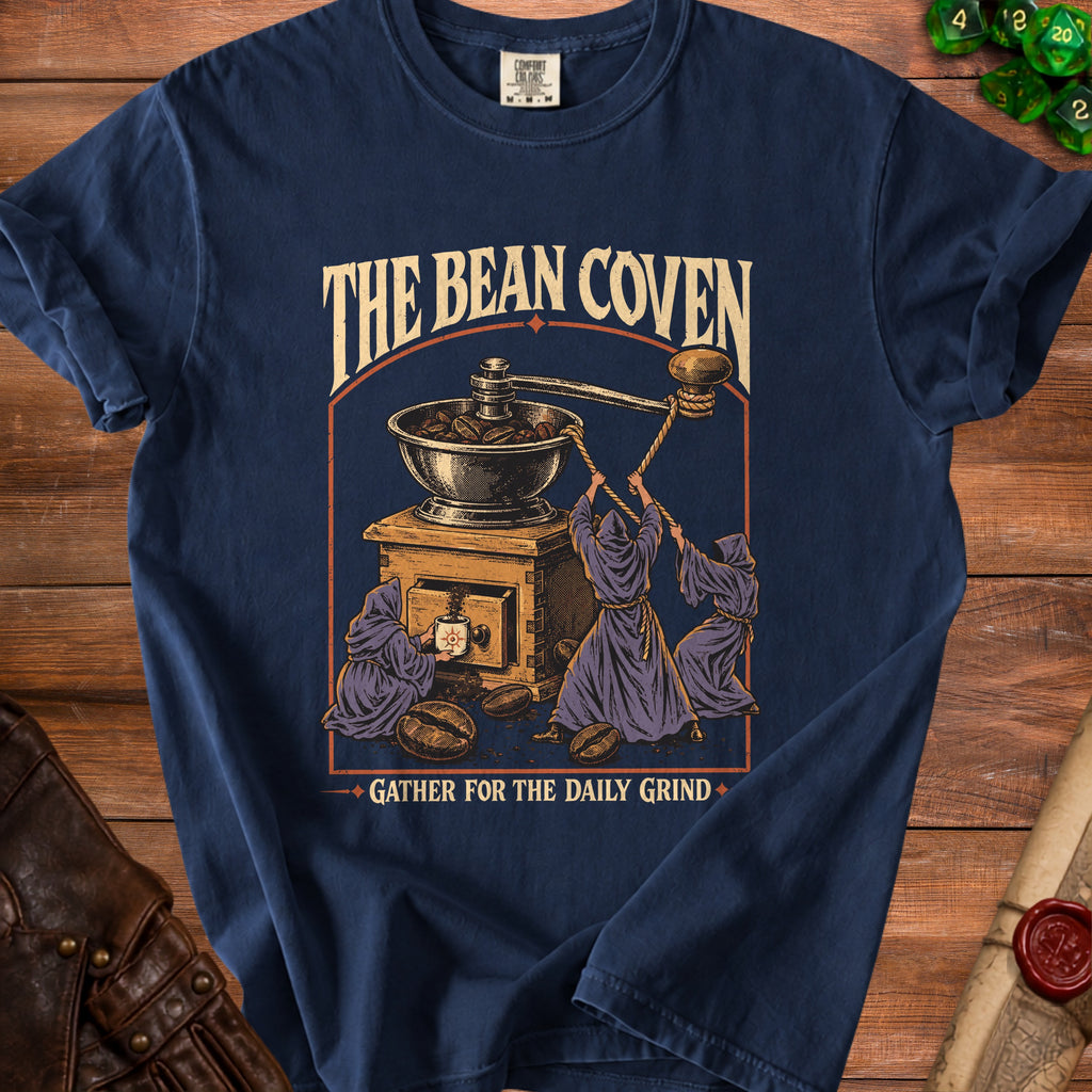 "The Bean Coven" t-shirt with robed figures grinding coffee beans, with text "GATHER FOR THE DAILY GRIND."
