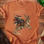Wizard riding a jackalope with a lasso, on a rust-colored t-shirt.