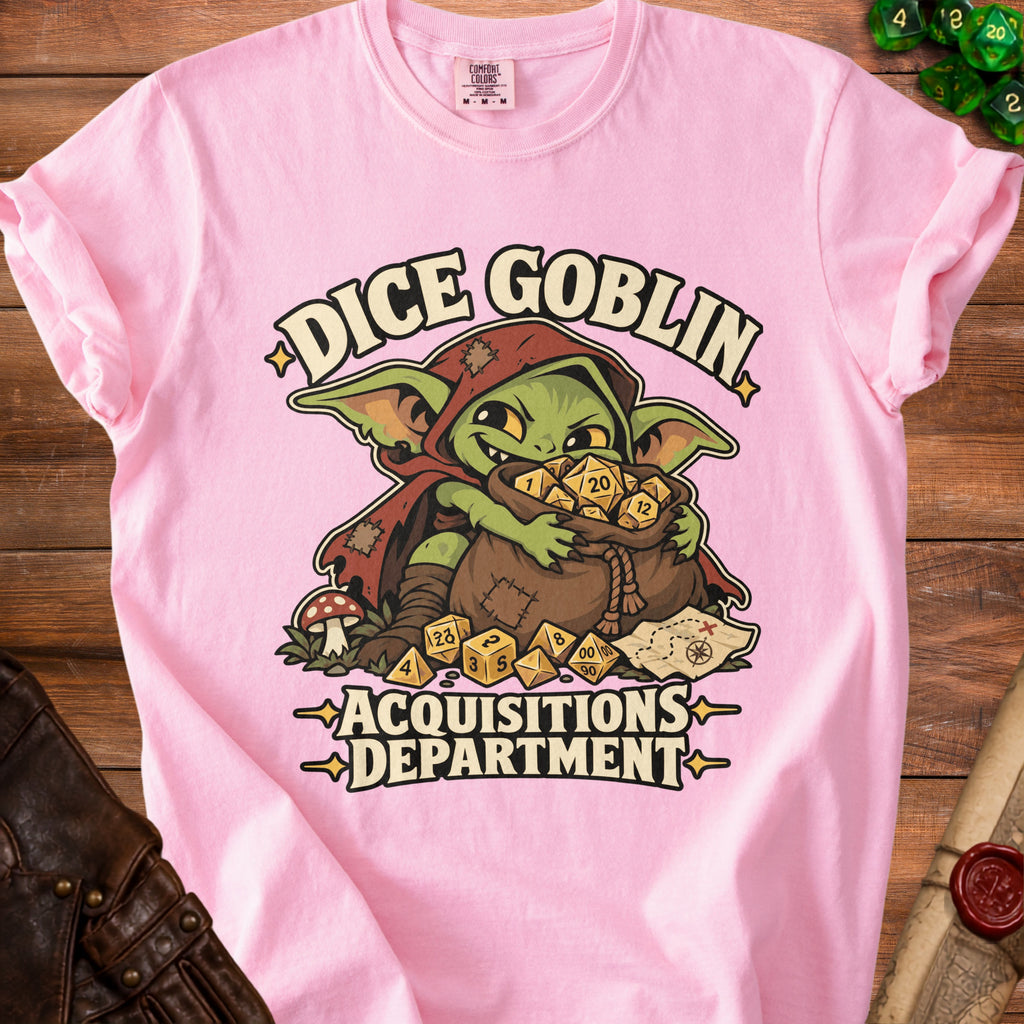Light pink t-shirt featuring a green goblin graphic hoarding dice and text reading Dice Goblin Acquisitions Department.