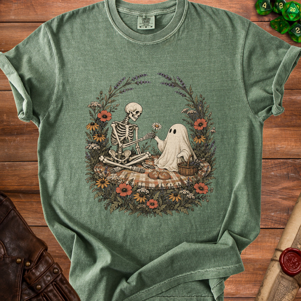 Green t-shirt with skeleton and ghost having a picnic, surrounded by flowers.