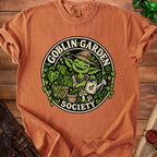 Orange t-shirt with "Goblin Garden Society" text and a happy goblin character gardening.