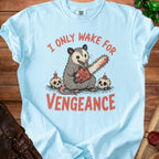 Light blue t-shirt with opossum holding chainsaw, skulls, and text "I ONLY WAKE FOR VENGEANCE".