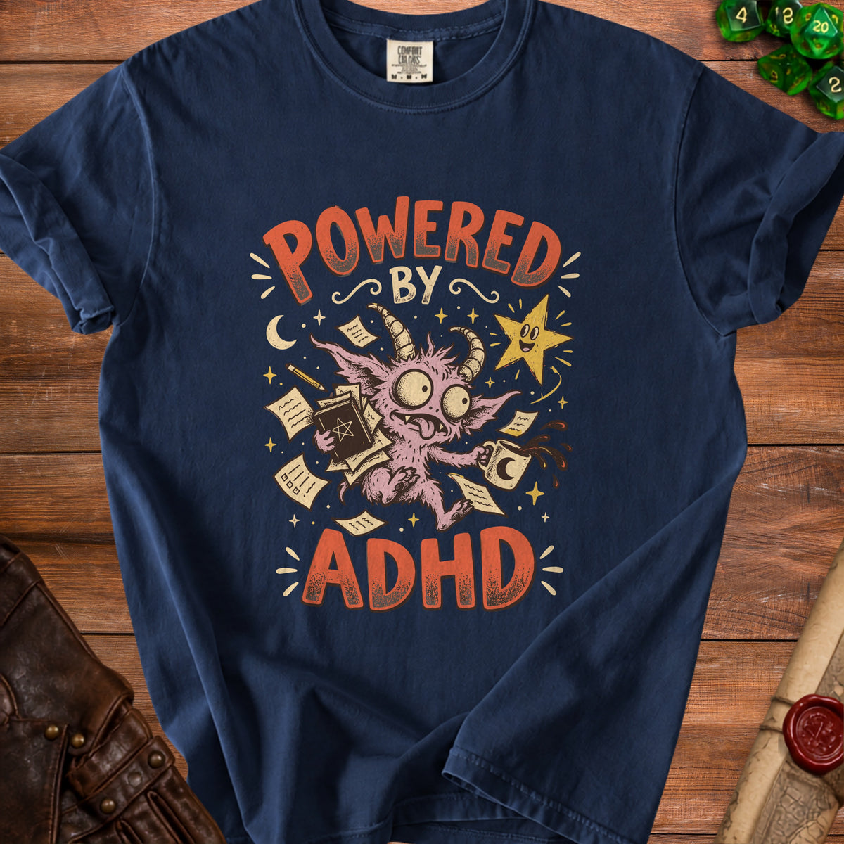 Dark blue t-shirt graphic with text "Powered By ADHD" and a cartoon monster.