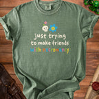 Green t-shirt with skull, flower, and text "just trying to make friends with necromancy".