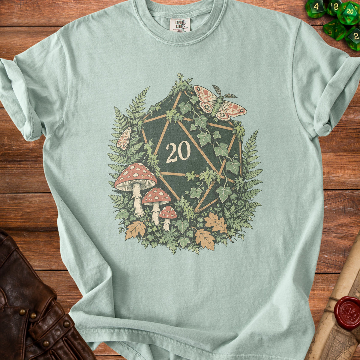 Green t-shirt with a D20 die design featuring mushrooms, ferns, ivy, and moths.