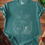 Teal t-shirt with cream outline print of bats, skeleton witch, and dandelions.