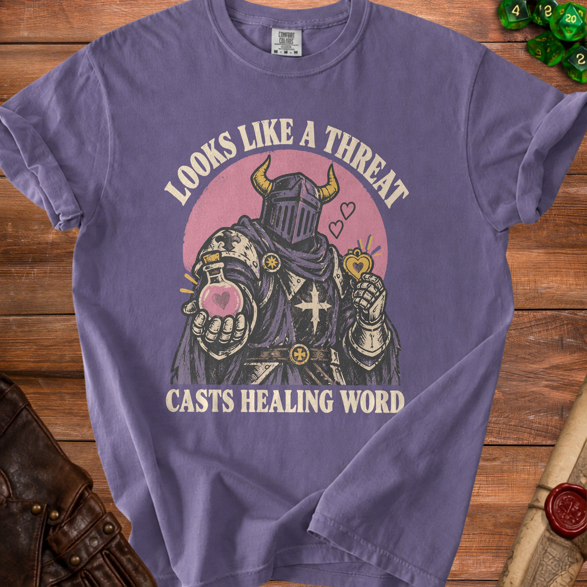 Purple t-shirt with a knight illustration and text "Looks like a threat casts healing word."