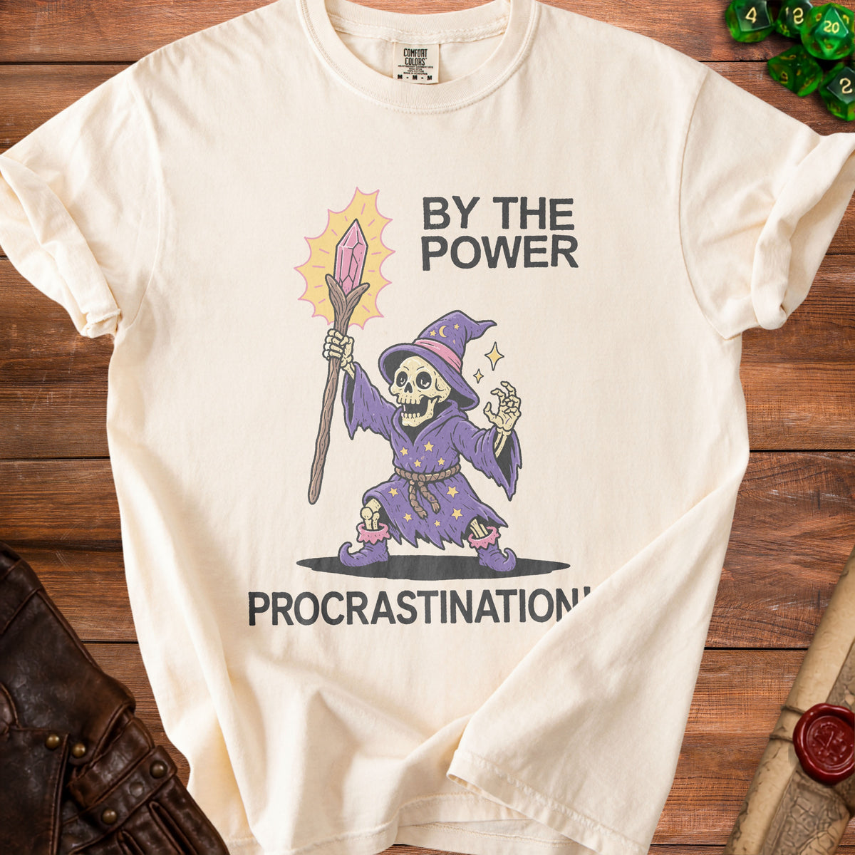 Cream t-shirt with a skeleton wizard casting a spell with text "BY THE POWER PROCRASTINATION".