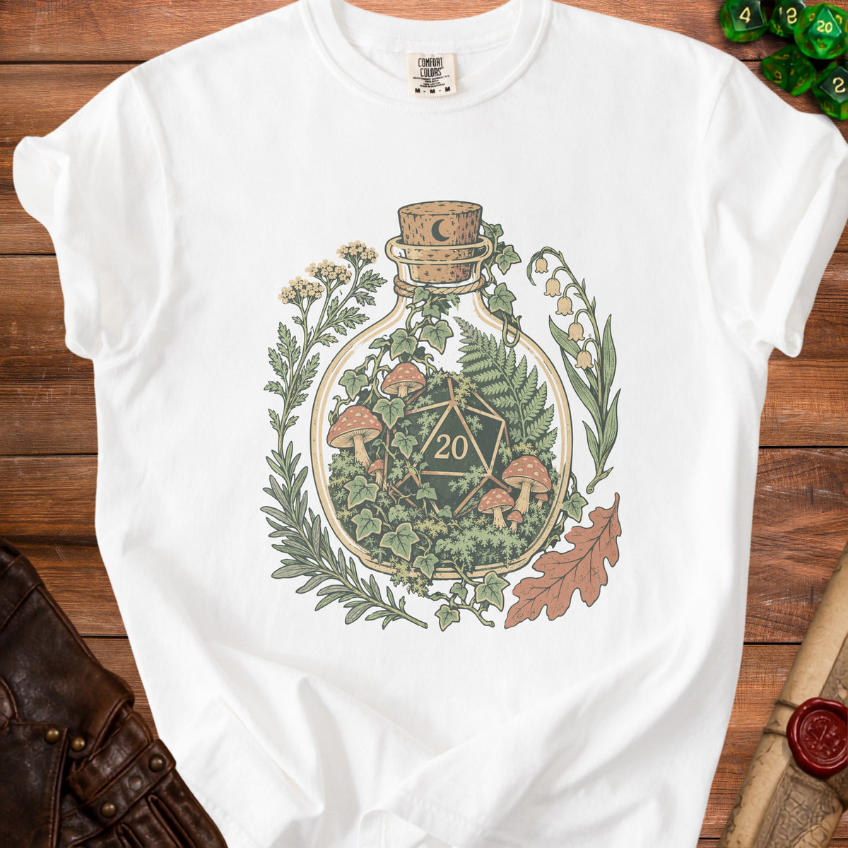White t-shirt with a bottle terrarium featuring dice, mushrooms, and foliage graphic.