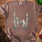 T-shirt graphic of skeleton in witch hat resting in hammock between trees with pumpkin.