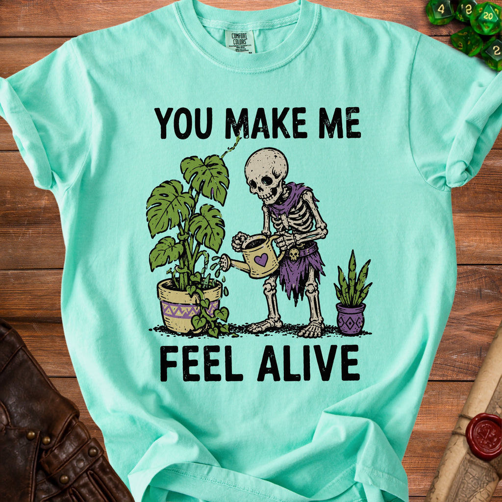 Skeleton watering plants with text "YOU MAKE ME FEEL ALIVE"