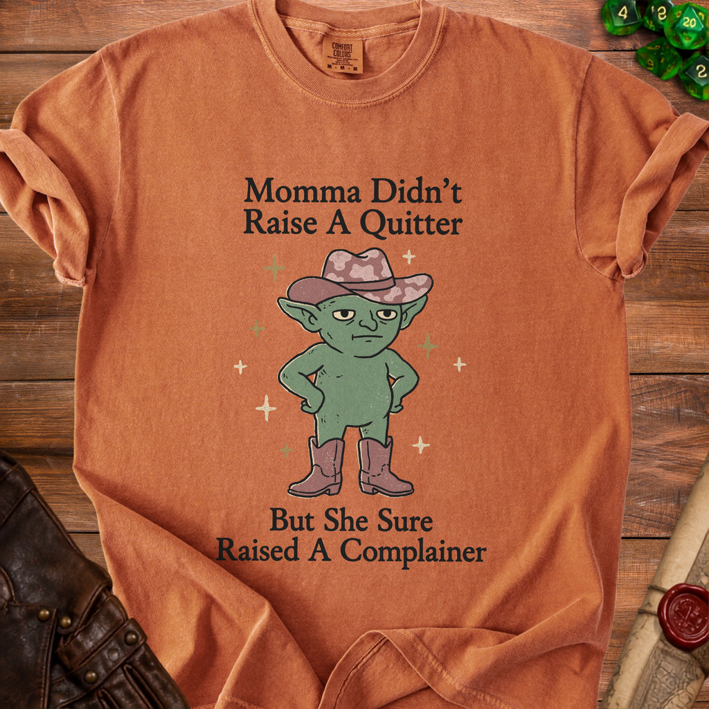 T-shirt with a green goblin wearing a cowboy hat and boots and the text "Momma Didn't Raise A Quitter But She Sure Raised A Complainer."