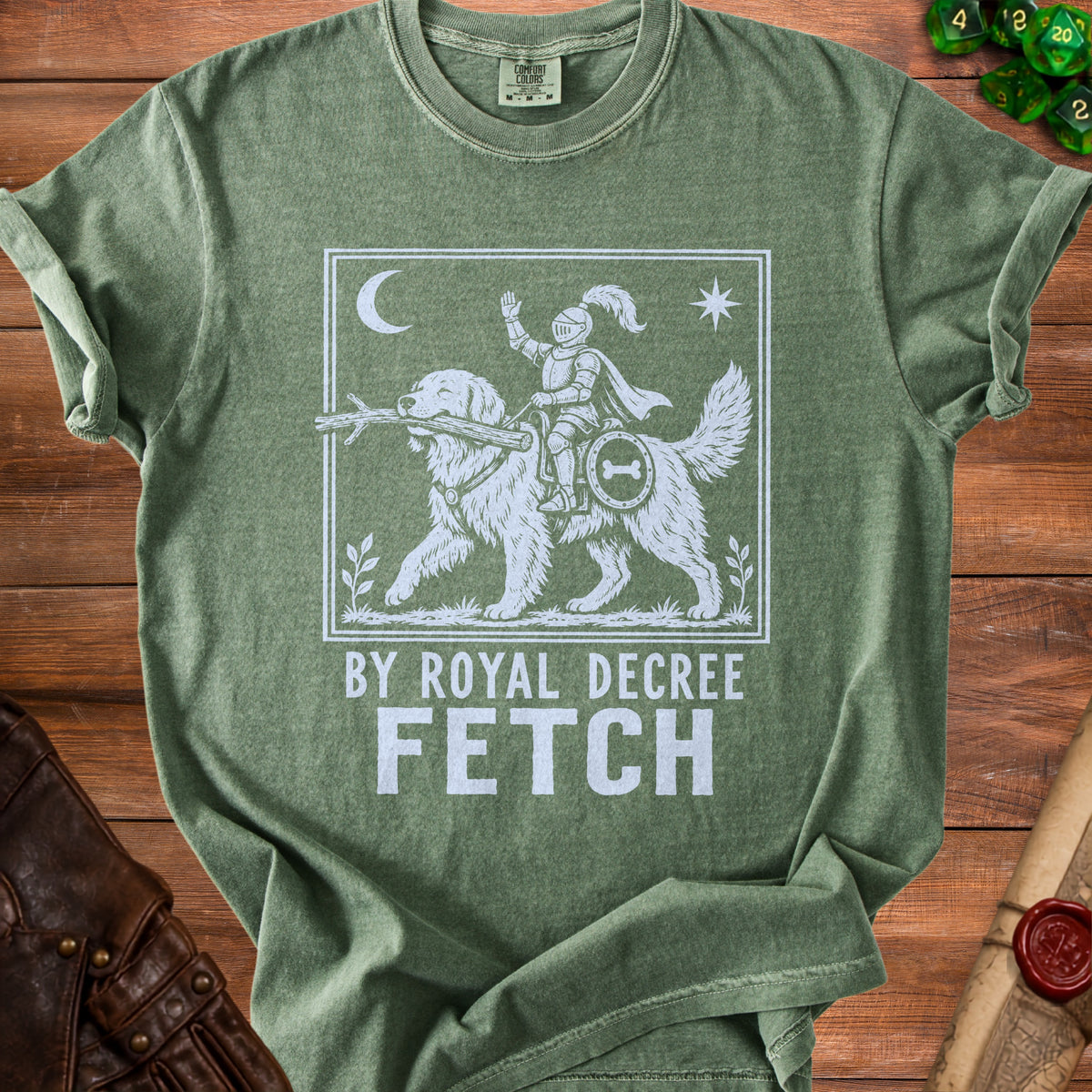 Green t-shirt with a white graphic of a knight riding a dog with "BY ROYAL DECREE FETCH" text.
