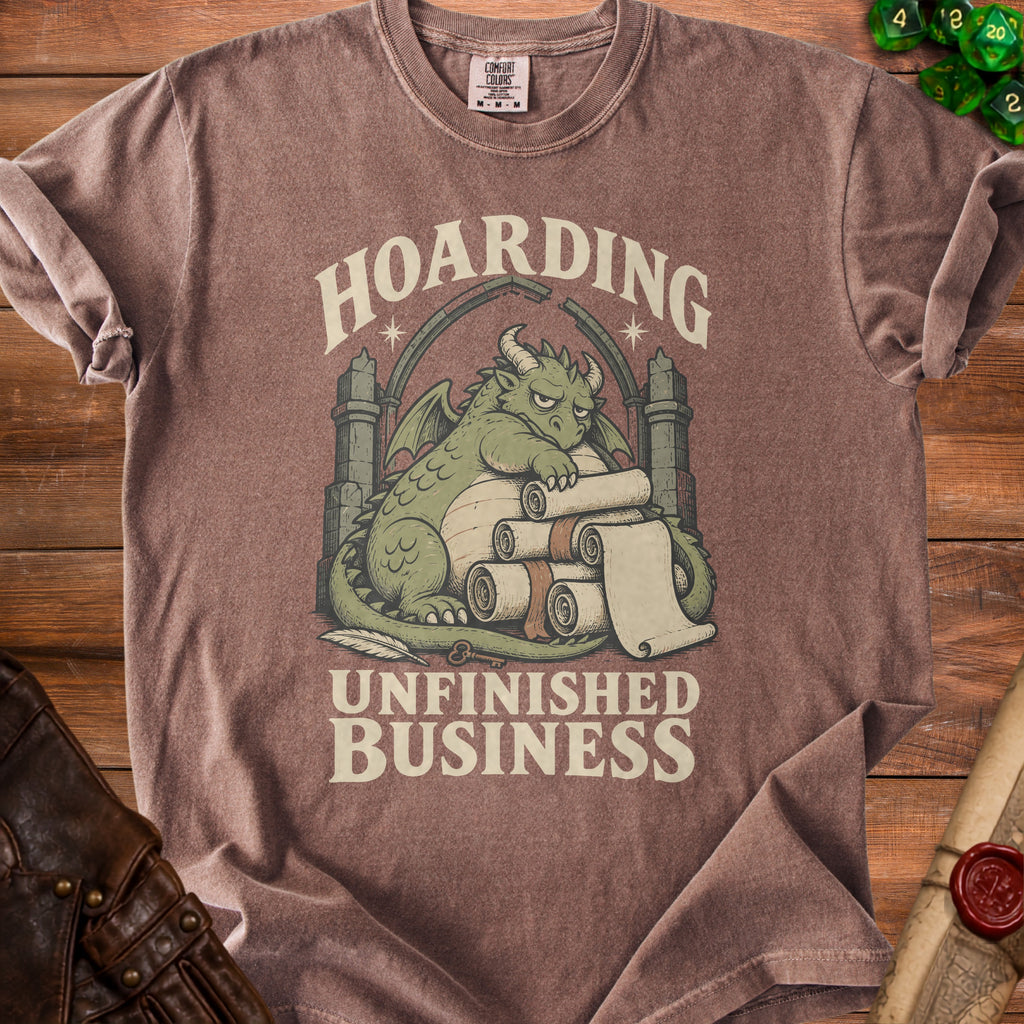 Brown t-shirt with a green dragon hoarding scrolls, reading "Hoarding Unfinished Business".