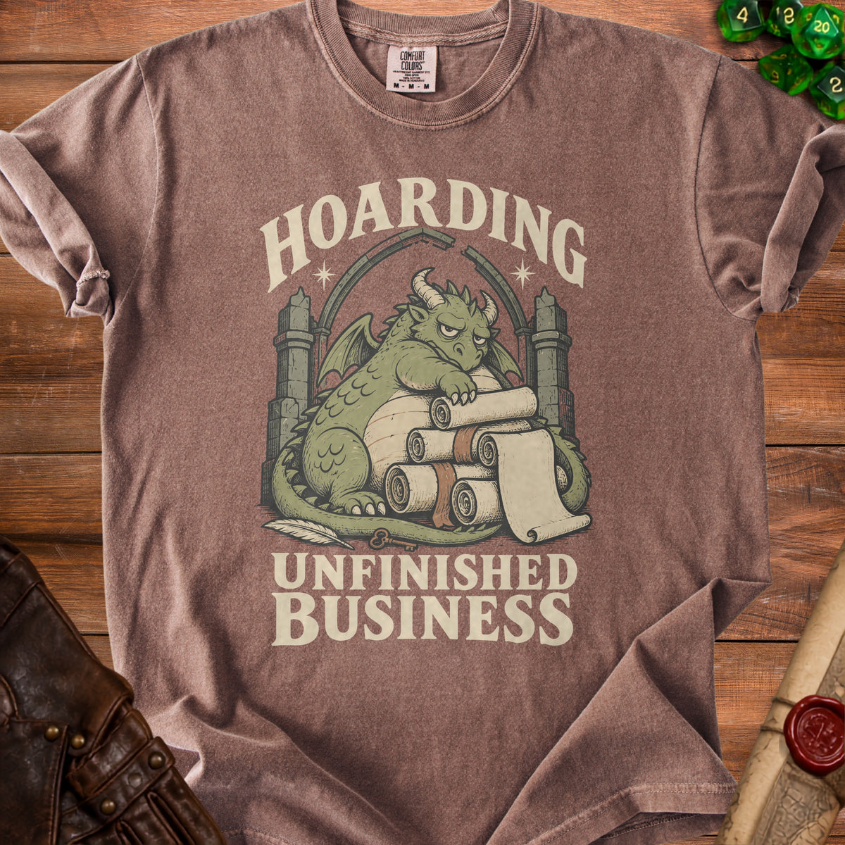 Brown t-shirt with a green dragon hoarding scrolls, reading "Hoarding Unfinished Business".