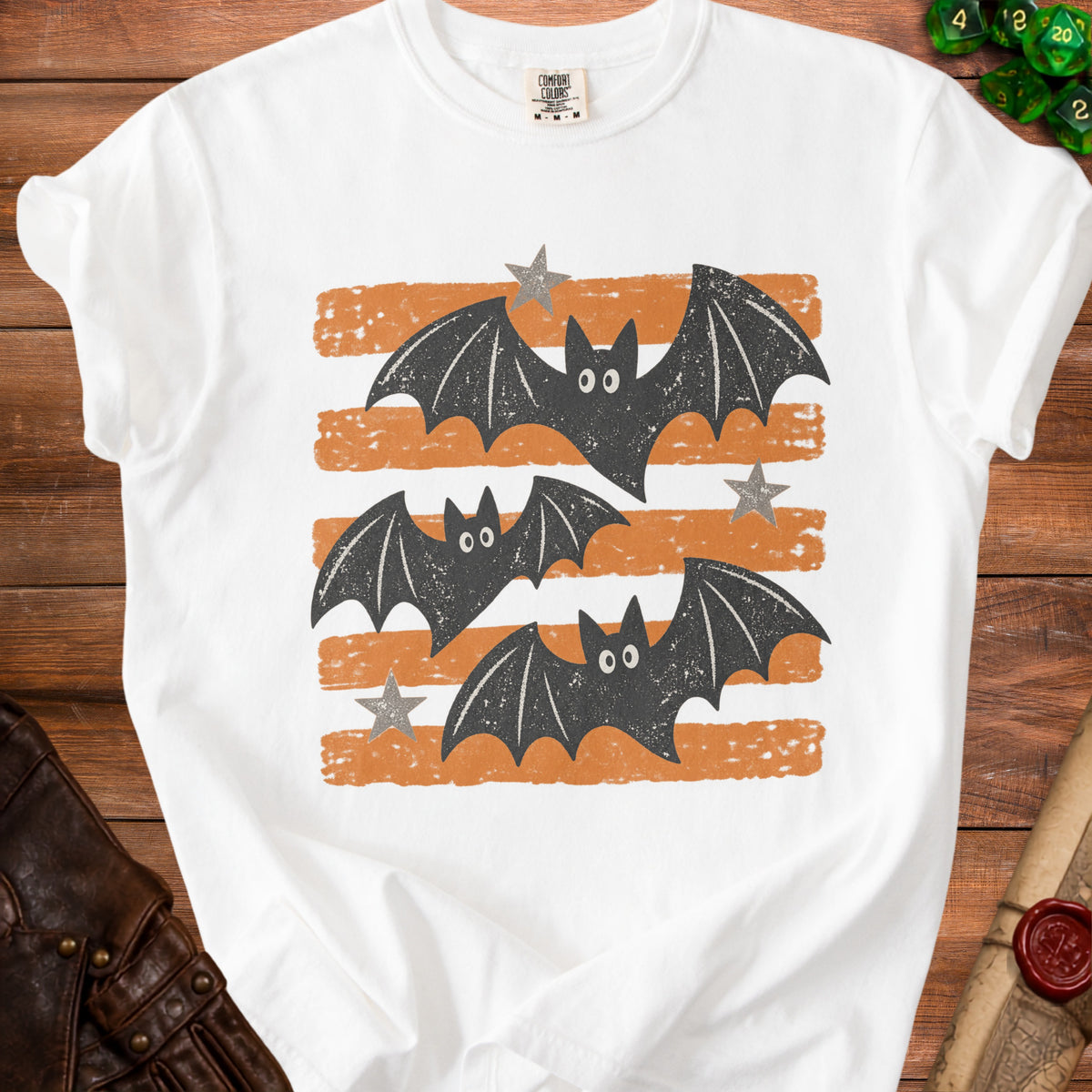 White t-shirt with a graphic of three charcoal bats and stars on orange stripes.