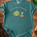 Green t-shirt with frog wearing a witch hat, holding a book with a ghost.