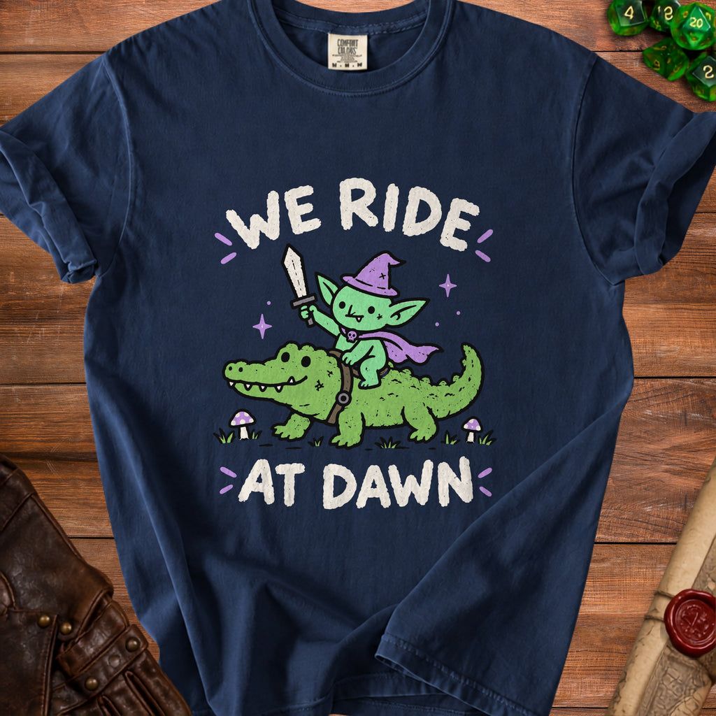 Dark blue t-shirt with "WE RIDE AT DAWN" text and cartoon goblin on alligator.