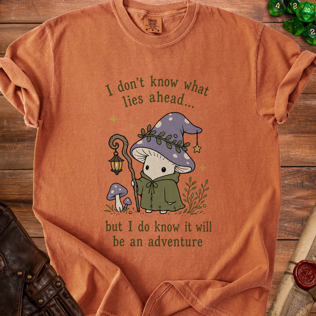 T-shirt with a mushroom character and the text "I don't know what lies ahead... but I do know it will be an adventure".