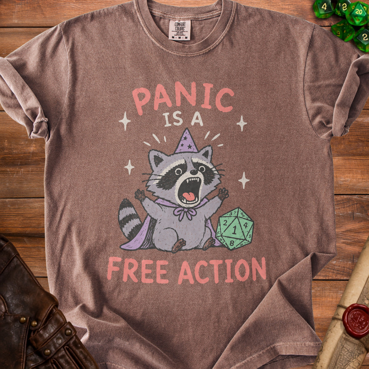 T-shirt with a cartoon raccoon wearing a wizard hat and cape, text "PANIC IS A FREE ACTION".